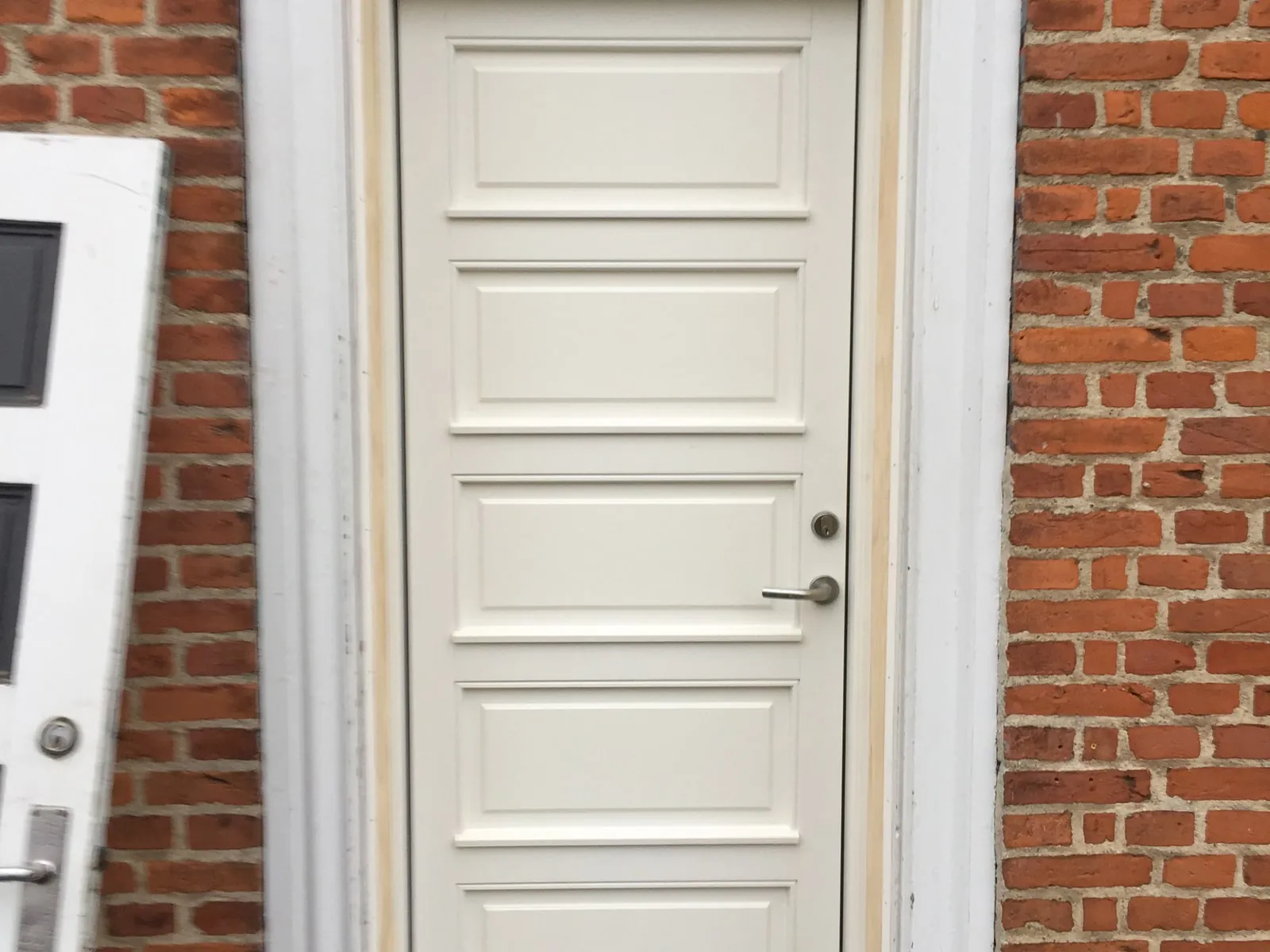 Ny hvid facadedør monteret i murstensfacade