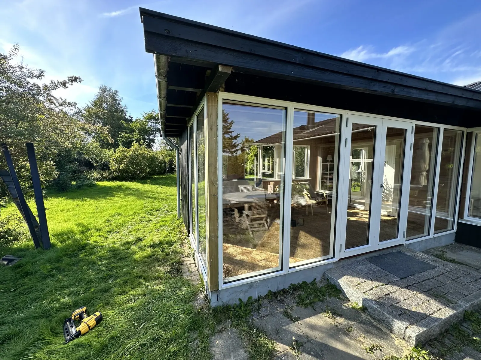 Hjørneparti af glasdøre i sommerhus set fra haven